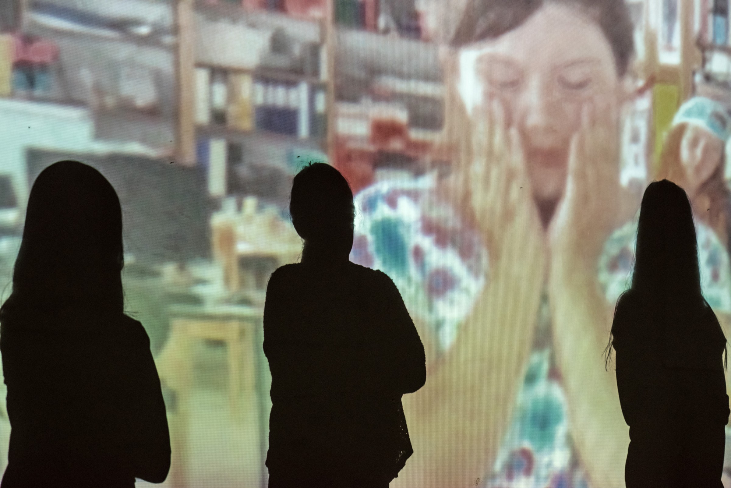 Shadows of three performers, an image of a sad girl projected on the wall