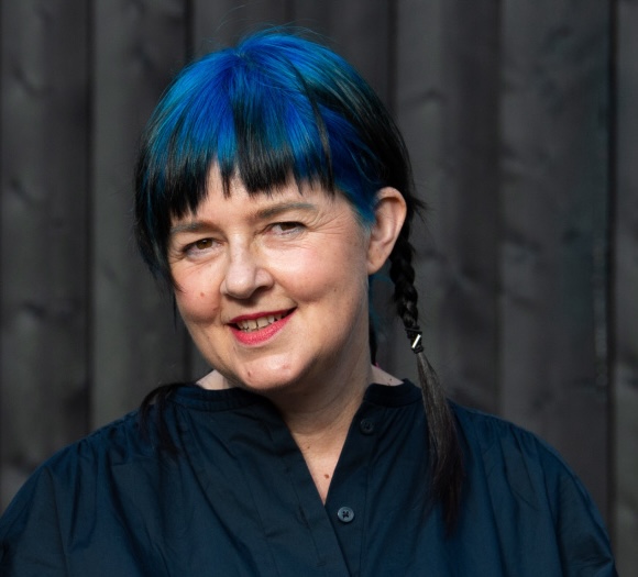 Portrait of Ruth Catlow: Person with a blue hair, smiling, looking at the camera.